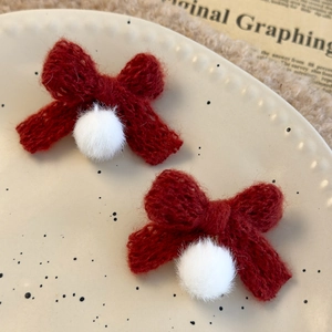Detailed shot of handmade red knitted bow earrings with soft white plush pom-poms