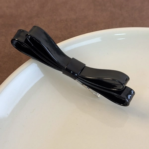 Fermaglio per capelli a doppio fiocco in pelle nera lucida con clip in metallo su piatto