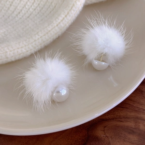 Winter white fluffy pom-pom earrings with pearls on a cozy knitted background