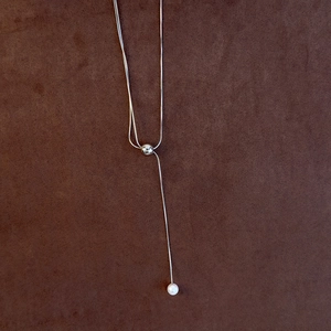 Close-up of adjustable long Y-shaped necklace with silver sliding bead and pearl charm