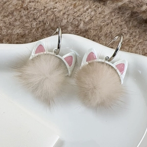 Nahaufnahme von Katzenohr-Pom-Pom-Ohrringen auf einem Keramiktablett mit Winter-Vibe