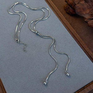 Detail of adjustable silver snake chain lariat necklace with polished round beads