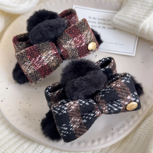 Detail of tweed plaid bow hair claw with faux fur balls and golden engraved button