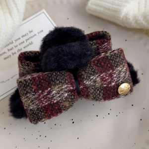 Detail of red plaid bow hair claw clip with black faux fur balls on a white plate