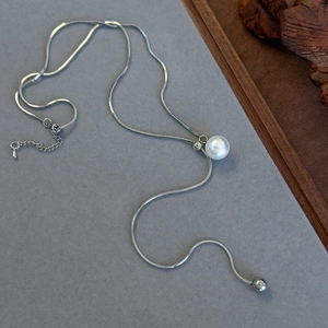Detail of adjustable silver snake chain necklace with pearl and Y-shaped sliding design