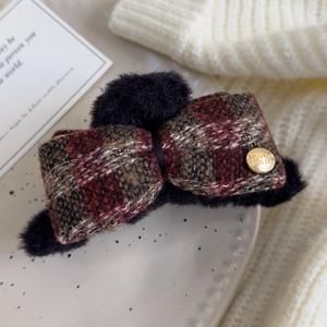 Detail of red plaid bow hair claw clip with black faux fur and engraved gold metal button