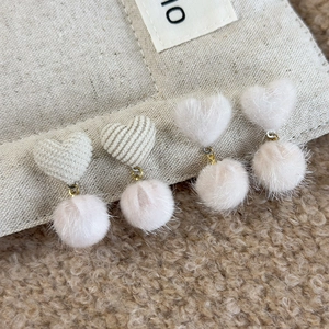 Detailed close-up of winter heart-shaped plush drop earrings set with soft faux fur pom-poms