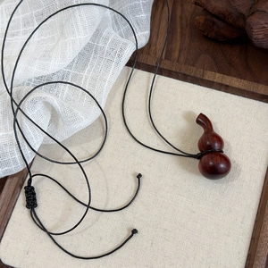 Détail du pendentif gourde en bois vintage avec grain brun rougeâtre sur cordon en cuir