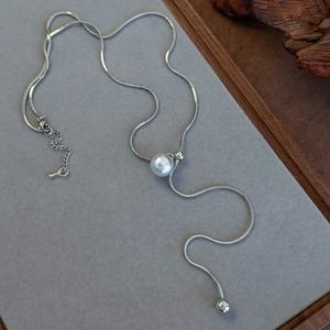 Detail view of adjustable silver snake chain necklace with pearl accent and metal beads