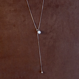 Macro detail of adjustable silver snake chain featuring a lustrous round white pearl pendant