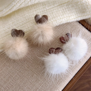 Detail of plush faux fur pompom accessories with brown plaid heart patterns in warm tones