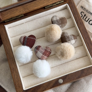 Detail view of plaid fabric hearts and plush pom-pom earrings in a wooden jewelry box