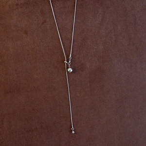 Detail of adjustable silver snake chain necklace with round metal beads and Y-shape design