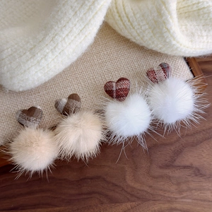 Detail of plush heart charms with plaid fabric patterns and fluffy faux fur pom poms