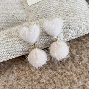 Detail of pink plush heart earrings featuring soft fur texture and gold link accents