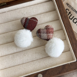 Detailed view of red plaid fabric heart stud earrings with soft white faux fur pom poms