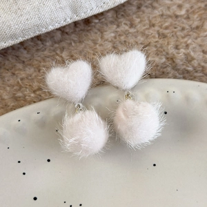 Detail view of white fuzzy heart earrings with soft plush pompoms and silver metal rings