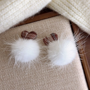 Detail of plush white pom-poms and brown plaid heart accents for winter earrings
