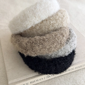 Detail of four fuzzy faux shearling headbands in white, tan, grey, and black colors