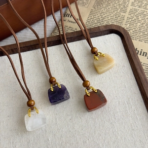Dettaglio dei ciondoli a forma di borsa in pietre bianche, viola, rosse e gialle