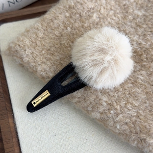 Macro d'une pince à cheveux avec pompon en peluche crème et texture en velours doux