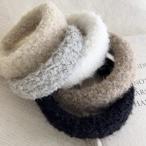 Detailed close-up showing five colors of plush lamb wool headbands in a soft fabric texture