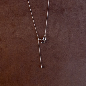 Macro shot of silver Y-shaped adjustable pearl necklace with interlocking double rings