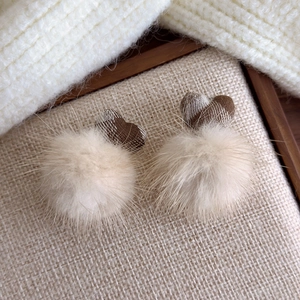 Detail of plush pom-pom earrings with brown plaid fabric hearts for winter outfits