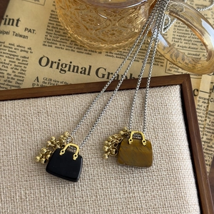 Close-up of retro bag charms with tiger eye stone and obsidian on delicate steel chains