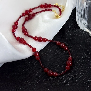 Vintage burgundy beaded necklace with adjustable gold clasp on elegant silk background