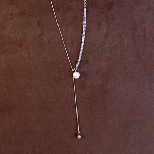 Detail of adjustable silver Y-necklace featuring crystals and a central white pearl