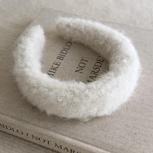 Close-up of fluffy white fleece headband with soft plush texture on a vintage book