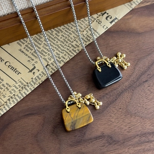 Macro shot of tiger eye and obsidian mini handbag pendant necklaces with silver chains