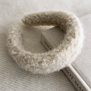 Detail of plush off-white lamb wool headband showing thick soft texture on books
