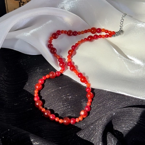 Gros plan du collier de perles rouges avec perles dégradées et fermoir mousqueton réglable