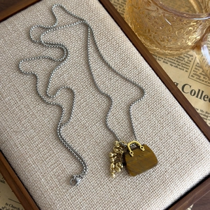Detail of vintage tiger eye stone bag pendant with golden charms and box chain