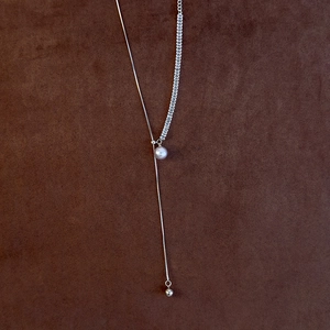 Detail of adjustable silver Y-necklace with pearl pendant and geometric chain texture