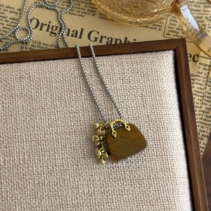 Detailed view of tigers eye stone handbag pendant on a silver box chain necklace