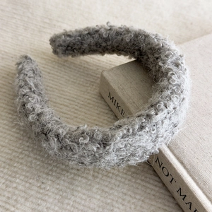 Detailed texture of thick grey plush faux fur headband resting on a neutral background