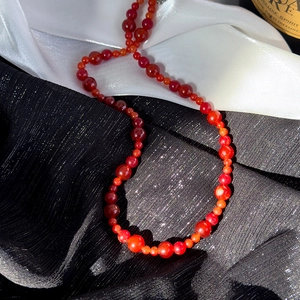 Détail macro du collier de perles d'agate rouge sur tissu noir et blanc contrasté