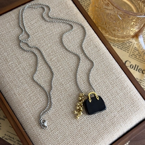 Detailed shot of retro handbag charm and gold beads on a silver ball chain necklace