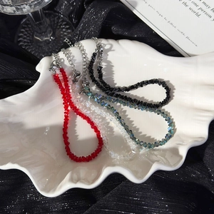 Set of four handmade beaded crystal bracelets in black, red, and clear on a white shell plate