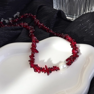 Collier vintage avec pierres concassées bordeaux et grosse perle sur plateau blanc