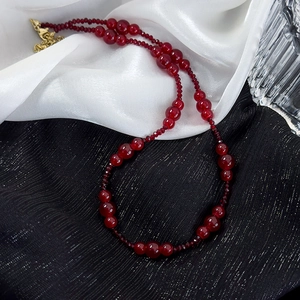 Close-up of vintage burgundy beaded necklace with gold lobster clasp on silk background