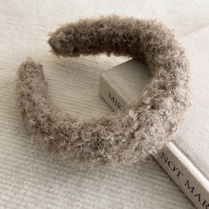 Close-up of thick plush lamb wool headband in khaki on a decorative book background