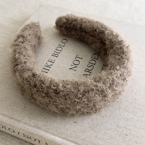 Detail of coffee brown fuzzy teddy fleece headband on a book with soft natural lighting
