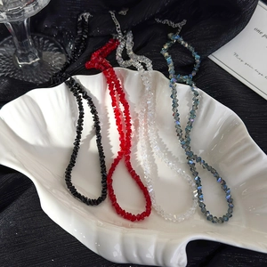 Detailed view of faceted crystal bead necklaces in four colors on a white shell tray