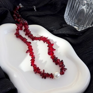 Vue détaillée du collier en pierres rouges irrégulières avec une perle blanche centrale