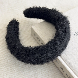 Detail of black faux fur headband with plush texture on minimalist white background