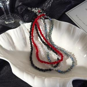 Macro detail of faceted crystal glass beaded necklaces in a white shell-shaped porcelain tray